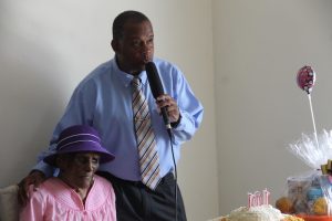 Hon. Eric Evelyn, Minister responsible for the Ministry of Community Development delivering congratulatory remarks to Ms. Ilene Smithen on the occasion of her 101stbirthday on June 20, 2018