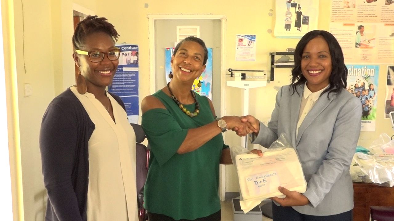 Dr. Jeanita Richardson, Professor at the University of Virginia hands over medical supplies to Mrs. Nicole Slack-Liburd, Permanent Secretary in the Ministry of Health while Dr. Kelsie Kelly looks on at the Charlestown Health Centre on June 19, 2018