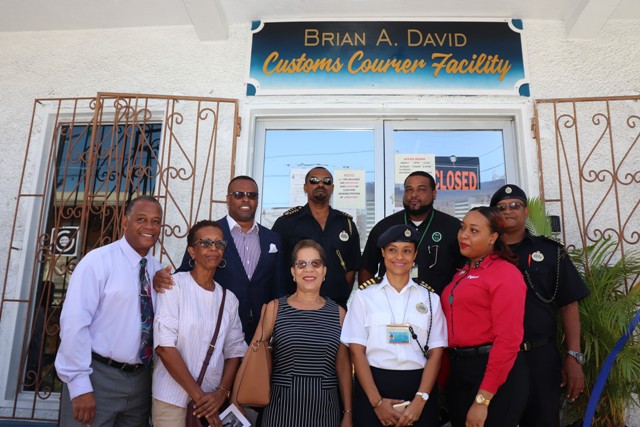 Photo caption: (L-r back row) Hon. Mark Brantley, Premier of Nevis; Mr. Cynric Carey, Deputy Comptroller of the Customs and Excise Department on Nevis; Mr. Sheldon David, son of the late Mr. Brian Anthony David; Mr. Kennedy DeSilva, Acting Comptroller of the St. Kitts and Nevis Customs and Excise Department. (Front row) Family members: Hon. Eric Evelyn; Ms Sheila Evelyn; Mrs. Joyce Powell-Broadbelt; Mrs. Kaymoye Carey and Ms. Shanelle David share a light moment after the renaming ceremony of the Customs Courier Facility in Charlestown on October 25, 2018