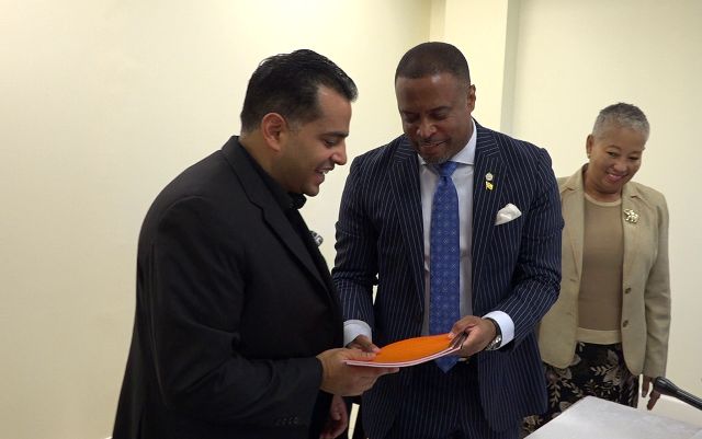 Hon. Mark Brantley, Premier of Nevis, exchanges copies of the signed agreement with Mr. Vishal Khann, President and Chief Executive Officer of Northern Pointe Development Ltd. on December 05, 2018, moments after they were signed, paving the way for the construction of a proposed Wyndham Grand resort at Long Haul Bay at Potworks on Nevis. Mrs. Hélène Anne Lewis, Legal Advisor in the Nevis Island Administration looks on