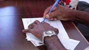 A beneficiary of the Federal government’s Poverty Alleviation Programme signs for his first $500 monthly benefit cheque at the Nevis Island Administration building in Charlestown on December 24, 2018