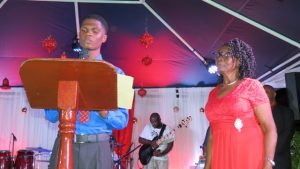 Mr. Recardoe Rodriquez, Youth Junior Minister of Tourism reads profile of Mrs. Zaiditor Olive Jeffers of Craddock Road, Patron of the annual Christmas Tree Lighting Ceremony in Charlestown on December 05, 2018
