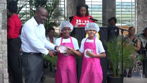 Mr. Randy Elliott, Director of Agriculture presents a trophy to joint 3rd place winners in the MyHealthyPlate Junior Chef Competition, to Mr. Yadav Pratyaksh and Ms. Khayla Claxton of the Nevis Academy, at the Nevis Performing Arts Centre courtyard on April 15, 2019
