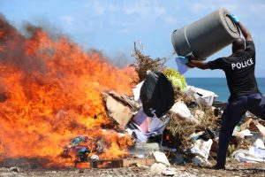 Inspector James Stephen, Head of the Nevis Task Force based at the Charlestown Police Station, feeds the fire burning more than EC$1million worth of illegal drugs in an operation at the Nevis Solid Waste Management Authority landfill at Long Point on June 13, 2019