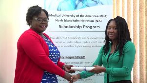 Hon. Hazel Brandy-Williams presents MUA/NIA Scholarship award to Ms. Dericia Bryant at the Ministry of Finance Conference Room in Charlestown on July 17, 2019, to pursue a Bachelor of Science in Interdisciplinary Studies with a focus on Special Education