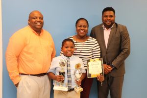 Mr. Ron Daniel and Mrs. Tresia Daniel and their son Rondre Daniel, winner in of the local leg of the 10th Annual OECS Courts Reading Competition; with Hon. Troy Liburd, Junior Minister of Education; at his office on November 18, 2019