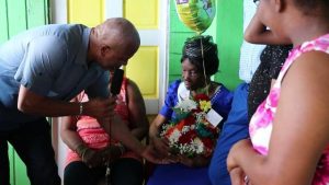 Hon. Spencer Brand, Area representative for the St. Paul’s Parish presenting Ms. Eliza “Liza Liburd Jeffers” Flanders of Hamilton with a fresh flower bouquet at her home in celebration of her 100th birthday on November 30, 2019