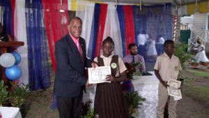 Hon Eric Evelyn, Minister of Social Development presenting Alexander Hamilton Scholarship certificate and $500 cheque to Ms. Noella Maynard form the Gingerland Secondary School, at the grounds of the Alexander Hamilton Museum in Charlestown recently. She is a 2020 beneficiary of the Alexander Hamilton Scholarship Fund 