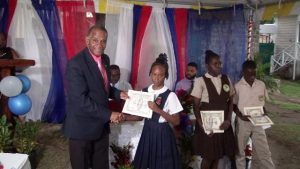 Hon Eric Evelyn, Minister of Social Development presenting Alexander Hamilton Scholarship certificate and $500 cheque to Ms. Kaya Williams-Mulraine from the Charlestown Secondary School, at the grounds of the Alexander Hamilton Museum in Charlestown recently. She is a 2020 beneficiary of the Alexander Hamilton Scholarship Fund 