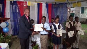 Hon Eric Evelyn, Minister of Social Development presenting Alexander Hamilton Scholarship certificate and $500 cheque to Mr. Jae-Ele Swanston from the Charlestown Secondary School, at the grounds of the Alexander Hamilton Museum in Charlestown recently. He is a 2020 beneficiary of the Alexander Hamilton Scholarship Fund