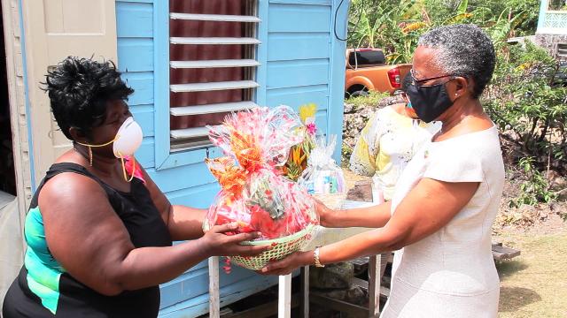 Her Honour Mrs. Hyleeta Liburd, Deputy Governor General on Nevis presenting a fruit basket to Mrs. Denise Browne for her mother-in-law, 103 year-old Mrs. Mary Brown of River Path, on behalf of His Excellency Sir Tapley Seaton, Governor General of St. Kitts and Nevis and the people of the Federation in observance of Centenarians Day celebrated on May 31, 2020