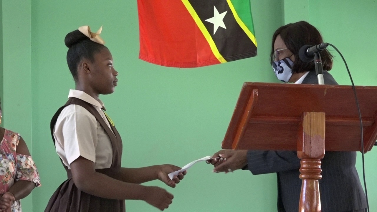 Ms. Nikelsia Kelly of the Gingerland Secondary School receives $1000 scholarship award from retired High Court Judge, the Honourable Pearletta Lanns at the school’s auditorium on August 26, 2020