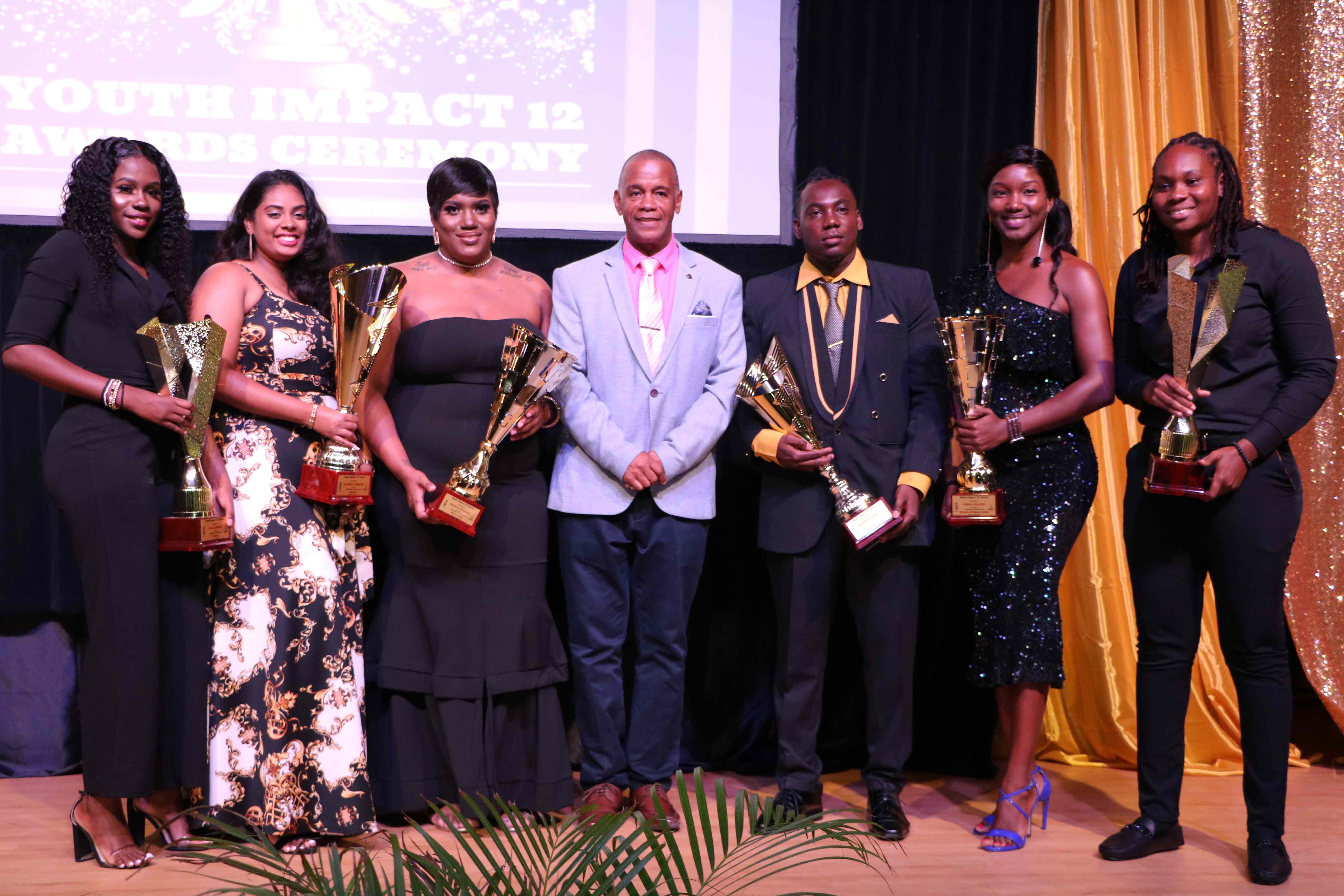 Hon. Eric Evelyn, Minister of Youth in the Nevis Island Administration (fourth from left) with the six awardees at the Youth Impact 12 Awards Ceremony hosted by the Department of Youth on August 12, 2020, at the Nevis Performing Arts Centre (l-r) Delcia Burke awarded for Volunteerism; Raveena Persaud awarded for Extraordinary Youth in Agriculture; Cecelia Stanley awarded for Youth in Entrepreneurship; Brandon Powell awarded for Youth in Technology; Verna Grant awarded for Education and Life-long Learning; and Melicia Clarke awarded for Sports Excellence