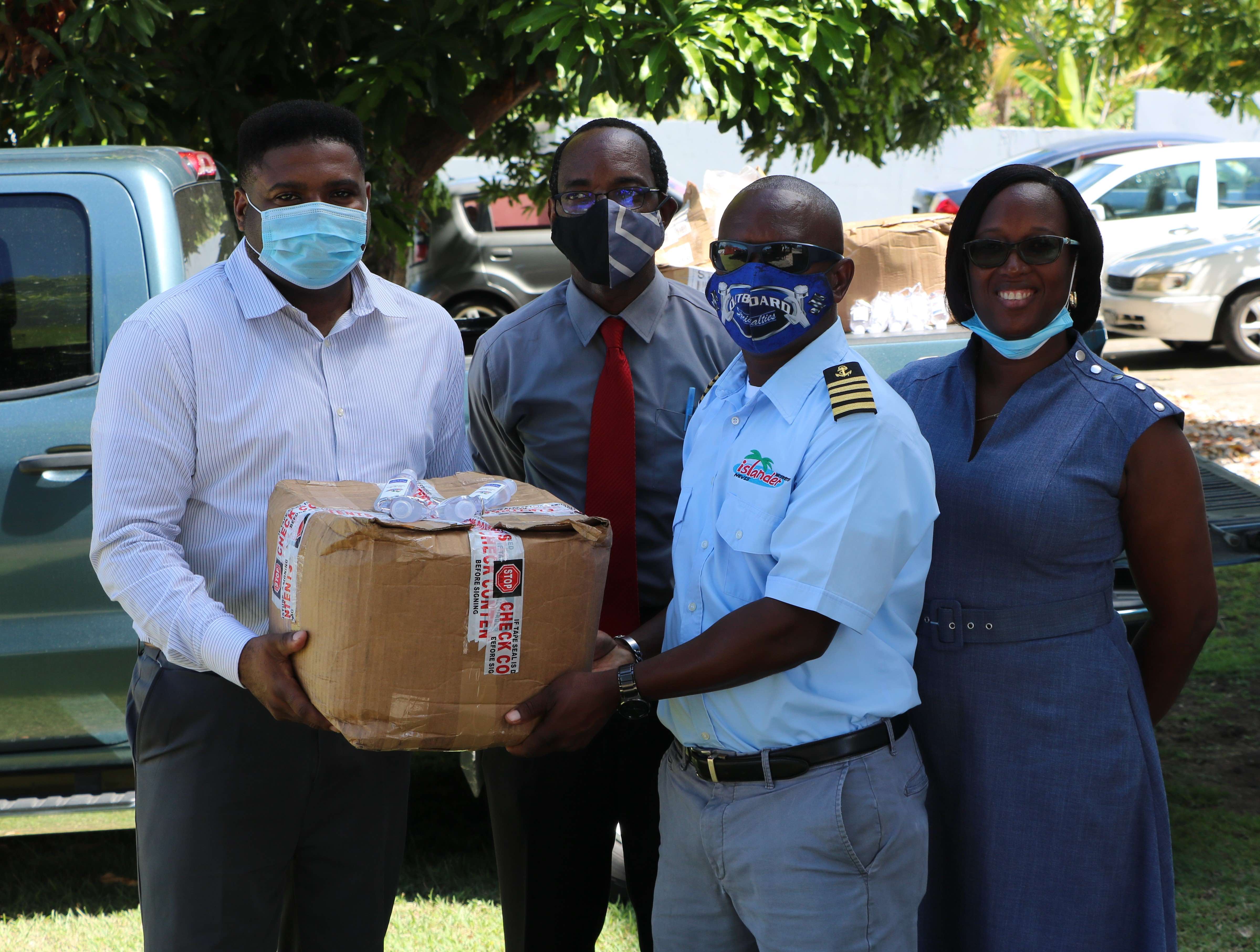 (l-r) Hon. Troy Liburd, Junior Minister of Education in the Nevis Island Administration; and Kevin Barrett, Permanent Secretary in the Ministry of Education, accepting a donation of 2000 bottles of hand sanitizer on September 14, 2020, from Mr. Wincent Perkins and his wife Mrs. Delvise Perkins, owners of local company Islander Watersports