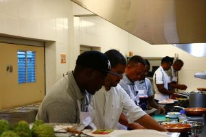 Chef Michael Henville (second from left) instructing participants at the Department of Gender Affairs “Men Can Cook” programme during a session at the Charlestown Primary School’s Cafeteria on November 23, 2020