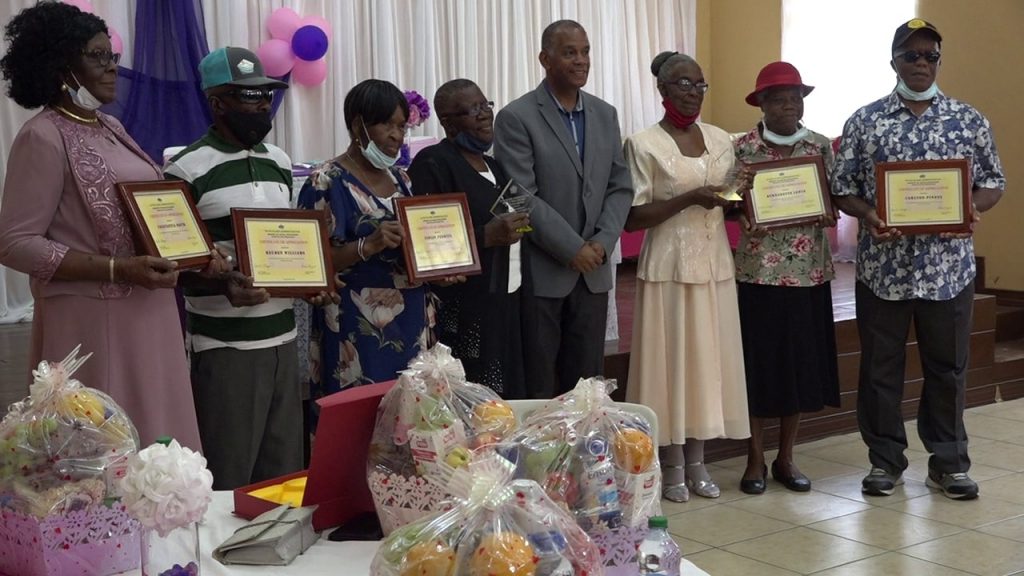 (l-r) Constantia David, Reuben Williams; Violet Perkins; Essie Delashley (caregiver); Hon. Eric Evelyn, Minister of Social Development in the Nevis Island Administration; Janet Herbert (caregiver); Bernadette Lewis; and Carlton Pinney during an October 29, 2020 Senior Citizens Awards Ceremony & Luncheon hosted by the Department of Social Services at the Jessups Community Centre
