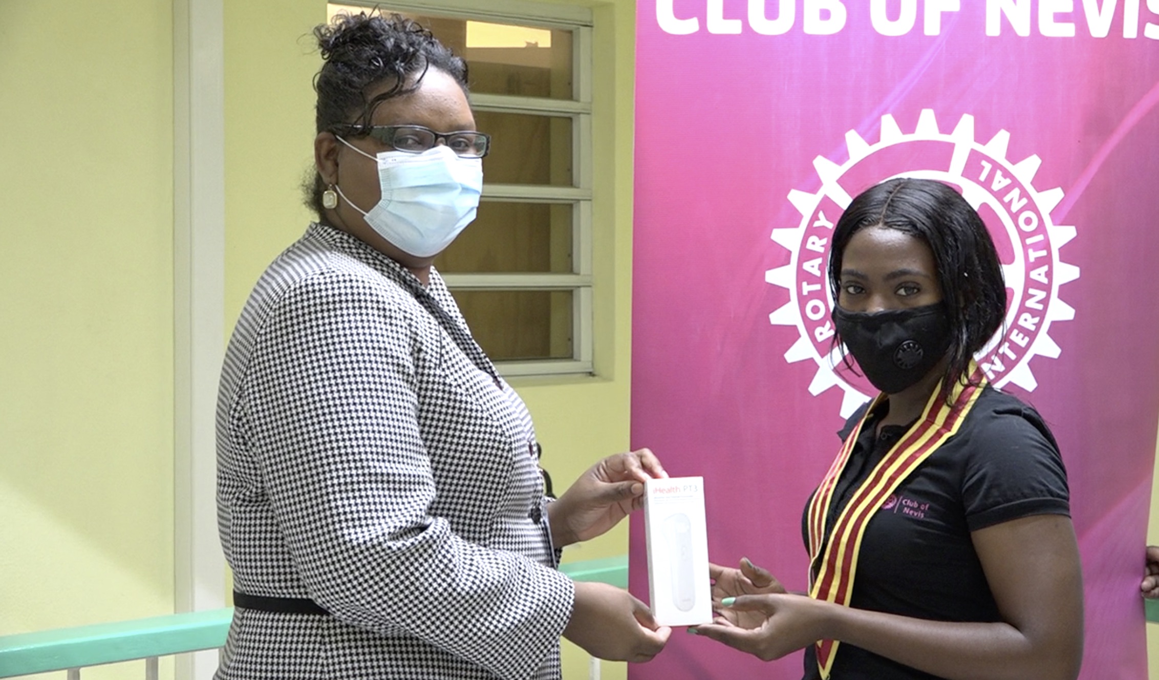 Ms. Zahnela Claxton, Principal Education Officer in the Department of Education receiving a gift of iHealth PT3 Infrared No-Touch Digital Forehead Thermometers from Ms. Asieah Smithen, Acting President of the Rotaract Club of Nevis on behalf of the club on February 03, 2021, at the Department of Education’s office in Marion Heights