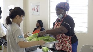 Ms. Wendy Tsai, a volunteer Nutritionist from Taiwan attached to the School Meals Programme assisting participants at a training session at the Charlestown Primary School’s cafeteria on March 10, 2021, in new meal preparation for the “Tour Around the World” initiative for primary school students 