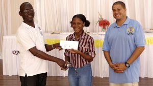 Mr. John Hanley, Permanent Secretary in the Ministry of Tourism, presents Ms. Jermella Browne, winner of the ministry’s first Creative Seafood Dish Competition with her prize on May 03, 2021 while Executive Chef Michael Henville, a judge looks on