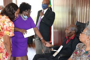 Hon. Hazel Brandy-Williams, Junior Minister of Health in the Nevis Island Administration congratulates Dr. Albert Linton Liburd Sr., a recipient of the 2020 Medal of Honour, while his wife Carla and other family members look on following the Investiture Ceremony at Government House in Bath Plain on September 09, 2021 