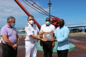 Hon. Alexis Jeffers presents a token of appreciation to Captain Vitaly Tsylke of the MS World Navigator cruise ship on its inaugural port call to Nevis on October 24, 2021, while Mr. Devon Liburd, Director of Sales and Marketing at the Nevis Tourism Authority (second from right) and Mario Pires, Hotel Manager onboard the vessel (extreme left) onboard the vessel look on