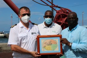 (L-r) Captain Vitaly Tsylke of the MS World Navigator presents a plaque to Hon. Alexis Jeffers, Acting Premier of Nevis during the cruise ship’s inaugural port call to the island on October 24, 2021, with Mr. Devon Liburd, Director of Sales and Marketing at the Nevis Tourism Authority (middle) looking on