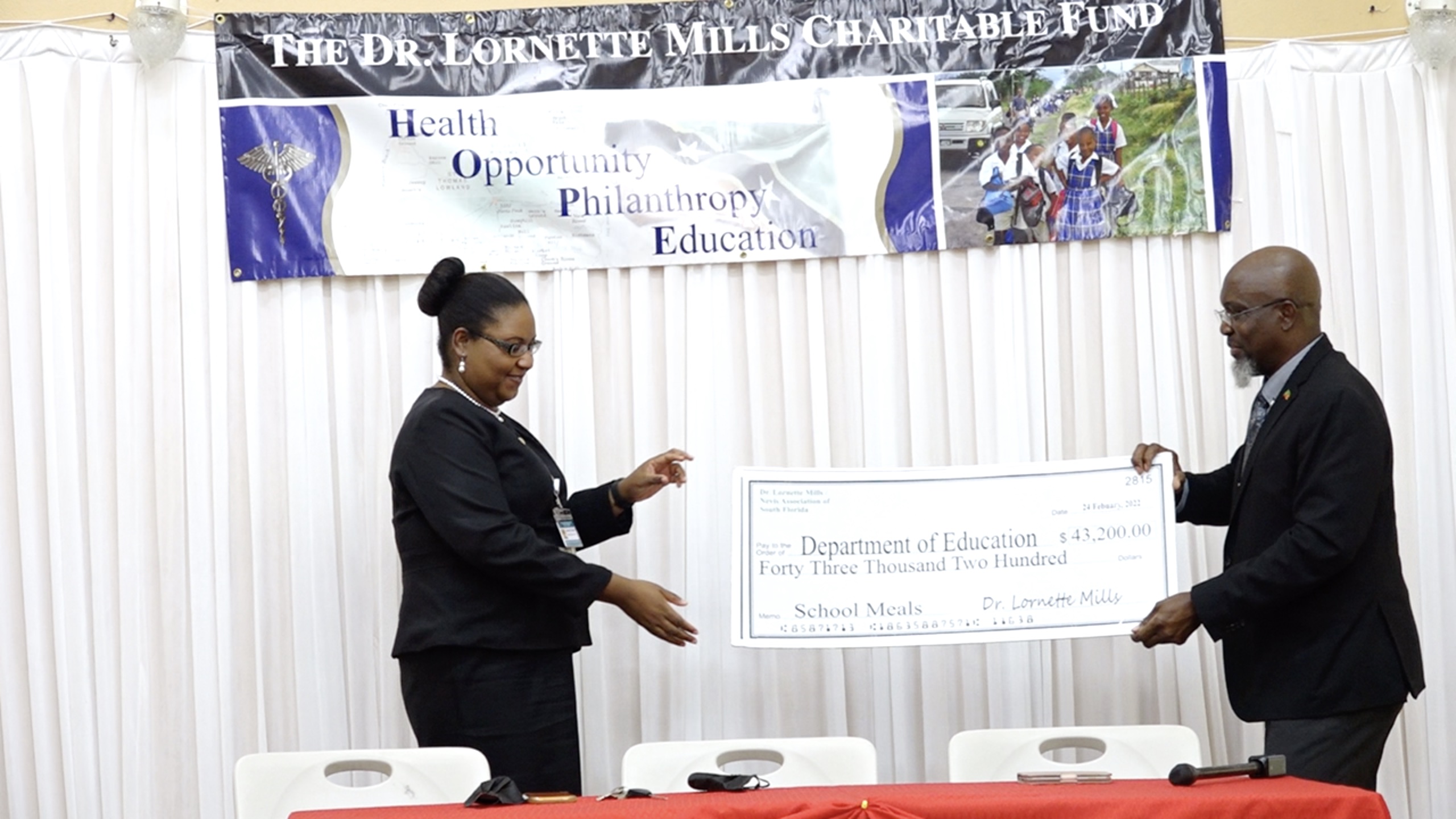 (l-r) Ms. Zahnela Claxton, Principal Education Officer in the Department of Education, receiving a cheque from the Dr. Lornette Mills Charitable Foundation through its representative Mr. Carlisle Powell on February 24, 2022, at a ceremony at the Jessups Community Centre