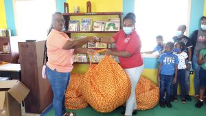 (l-r): Ms. Regan Jeffers, Secretary of the Butlers Enhancement and Improvement Association presenting bean bags to Ms. Chrislin Jeffers, Deputy Principal St. James Primary School on February 04, 2022