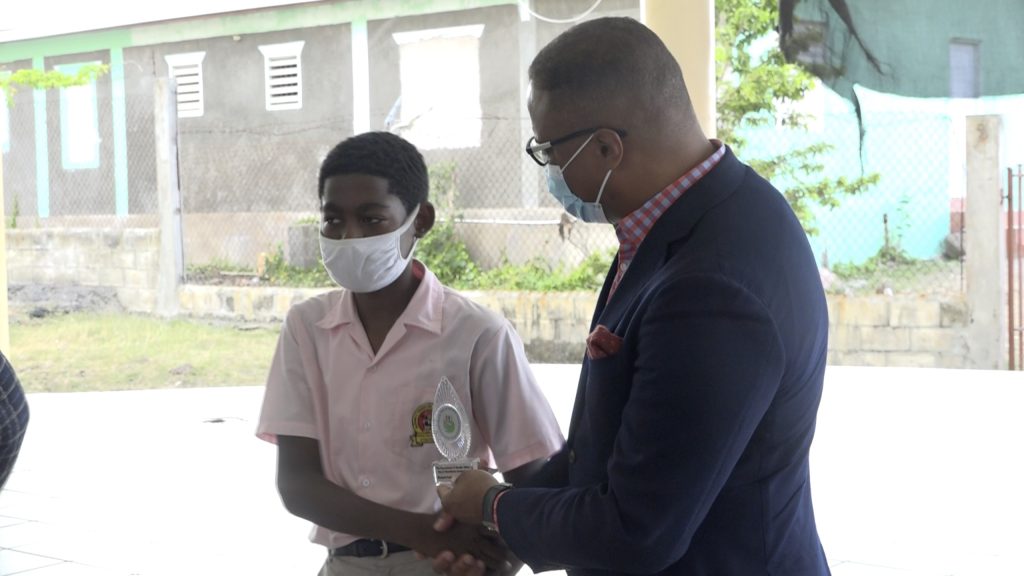 Hon. Mark Brantley, Premier of Nevis, Minister of Health and Gender Affairs and Minister of Education, Area Representative for St. John's Parish, presents award to Joshua Santos of Elizabeth Pemberton Primary School in observance of International Day of the Boy Child 2022