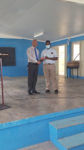 Hon. Spencer Brand, Area Representative for St. Paul's Parish, presents award to Nevroy Willock-Manners of Charlestown Secondary Primary School in observance of International Day of the Boy Child 2022