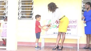 Ms. Shelisa Martin Clarke, Permanent Secretary in the Ministry of Health and Gender Affairs, presents award to William Guy III of Montessori Academy in observance of International Day of the Boy Child 2022