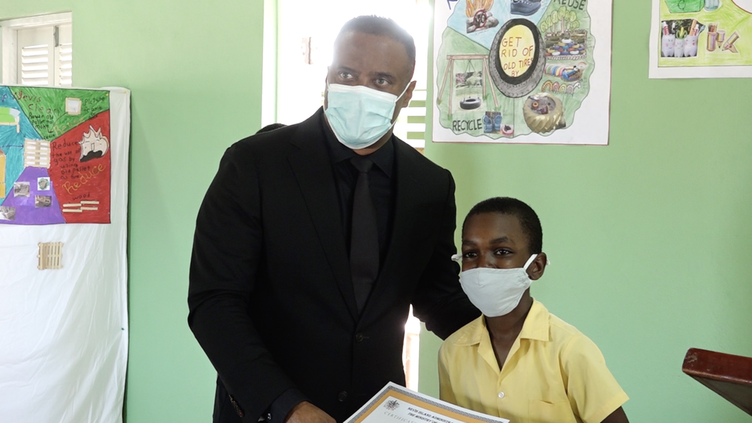 Hon. Mark Brantley, Premier of Nevis and Minister of Tourism, presents Hildreth Tross of the Cecele Browne Integrated School with gifts for emerging as the winner of the Ministry of Tourism’s 2022 Environmental Poster Contest