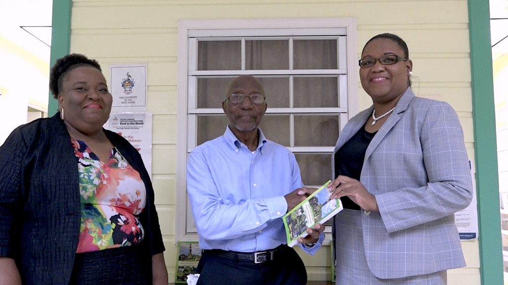 Author Mr. Hanzel Manners hands over copies of his book “Beyond The Bush & More” to Ms. Zahnela Claxton, Principal Education Officer in the Department of Education, on November 10, 2022, for primary and secondary school students on Nevis in the presence of Ms. Londa Brown, Assistant Principal Education Officer (left)