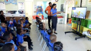 Hon. Troy Liburd, Minister of Education on Nevis, and students look on while Ms. Samika Warner, Supervisor of the Charlestown Preschool uses the 42-inch Samsung smart television on a mobile stand presented to her on behalf of the school on February 10, 2023
