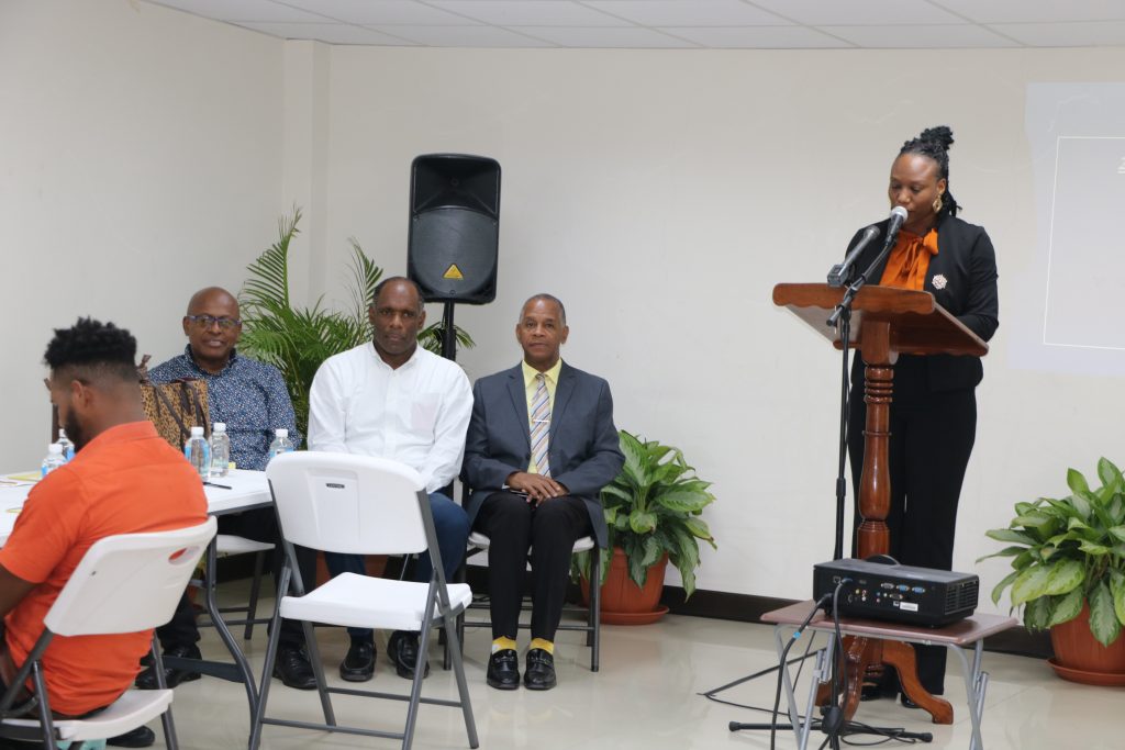 Hon. Latoya Jones, Special Advisor to the Premier of Nevis on community matters delivering remarks at the start of the 2nd Annual Financial Management Workshop, hosted by the Premier’s Ministry in the Nevis Island Administration at the Malcolm Guishard Recreational Park on May 10, 2023, with (seated left to right) Hon. Eric Evelyn, Deputy Premier of Nevis; Mr. Colin Dore, Permanent Secretary in the Ministry of Finance; and Mr. Laurie Lawrence workshop facilitator